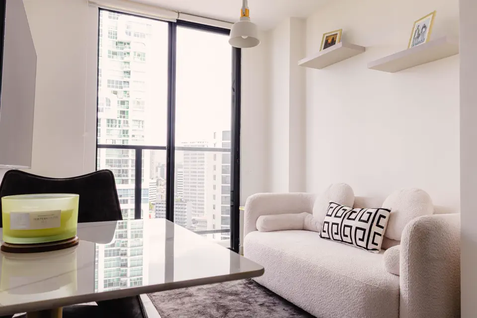 Helles Wohnzimmer einer Ferienwohnung mit Sofa, Esstisch und Blick über die Stadt