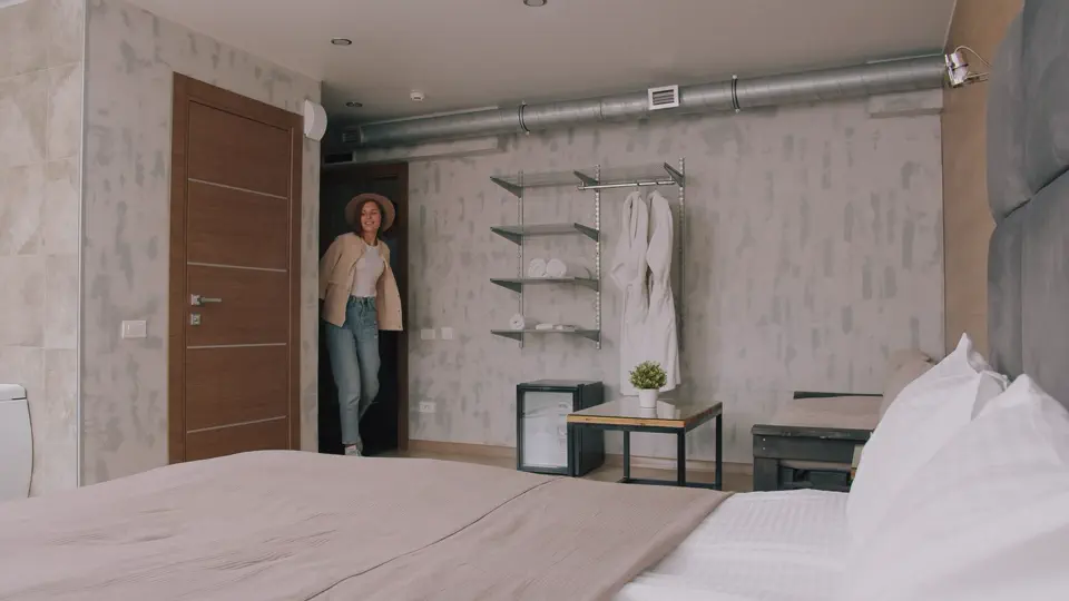 Gast betritt ein vorbereitetes Zimmer mit bezogenem Bett und frischer Bettwäsche