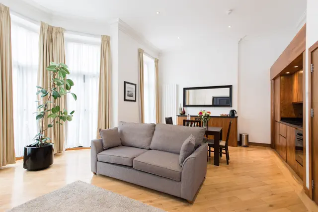 Wohnzimmer einer Ferienwohnung mit Sofa, Sesseln, Esstisch und gepflegten Oberflächen